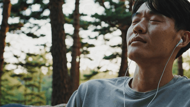 Man relaxing with earphones in a forest