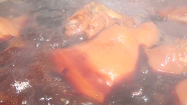 Pig's feet cooked in brown broth in a large pot in the kitchen