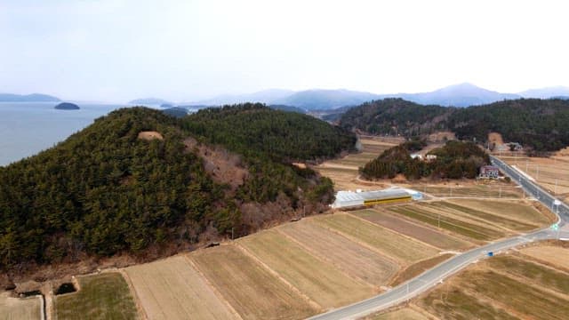 Farmlands and hills near a scenic coastline on a cloudy day