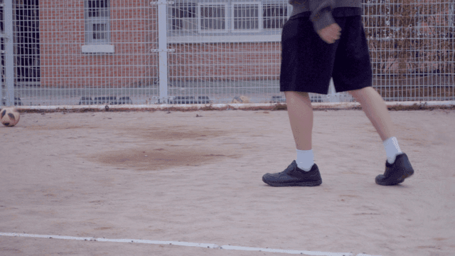 모래 운동장에서 축구를 하는 사람