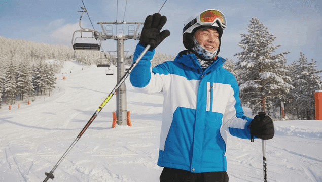 스키장 리프트 아래 웃으며 스키타고 내려가는 젊은 남자