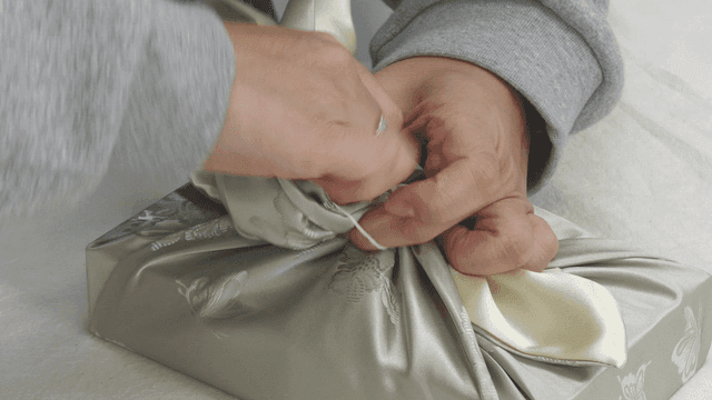 Hands wrapping gifts with traditional bojagi