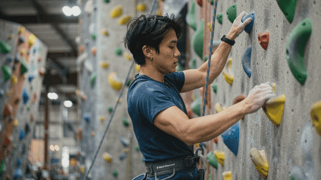 Man climbing indoor rock wall with concentration