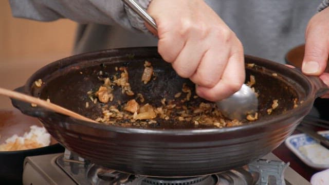 프라이팬에 눌러붙은 볶음밥을 숟가락으로 긁어내는 모습