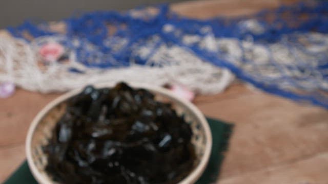 Basket of fresh seaweed on a wooden table.