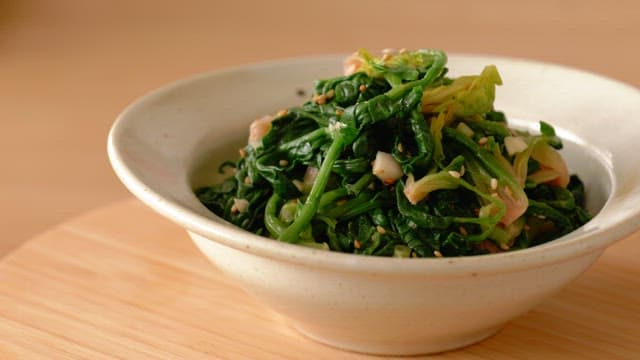 Spinach side dish in ceramic bowl on wooden table