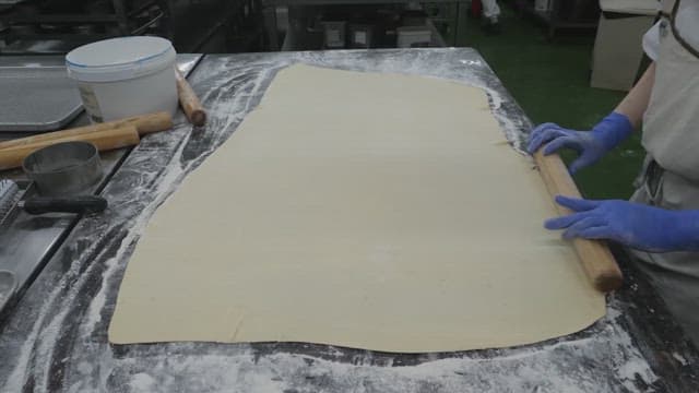 Rolling out dough with a rolling pin in a bakery kitchen