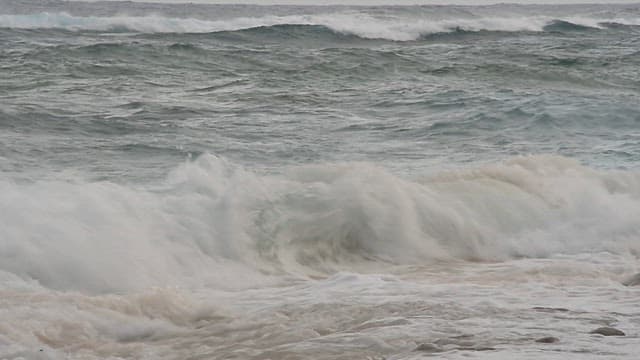 Waves crashing on a sandy beach on an overcast day