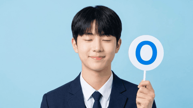 O 표시 팻말을 들고 있는 남학생