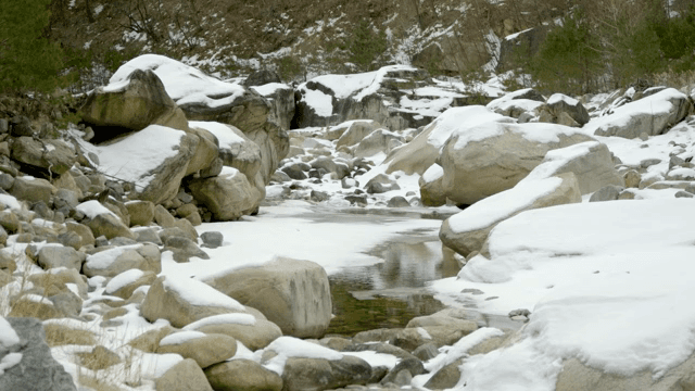 Snow-covered rocks and a flowing stream