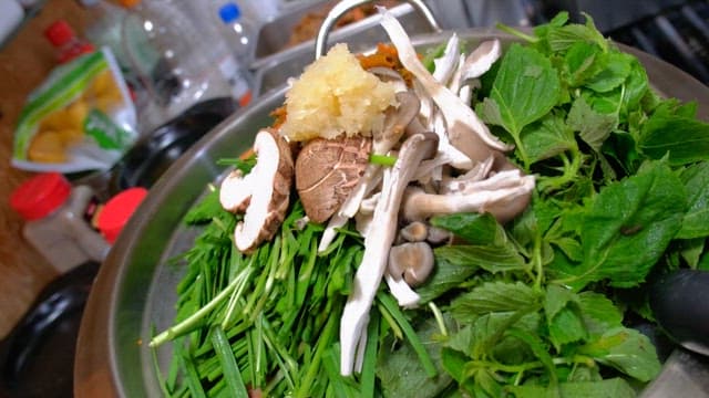 Fresh greens and mushrooms in a metal bowl for hotpot dish