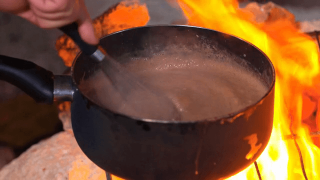 불 위 냄비에서 초콜릿 반죽 젓기