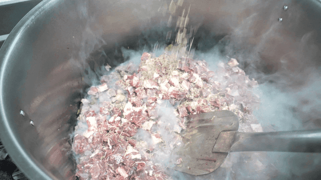 Rosemary sprinkled on meat in large pot