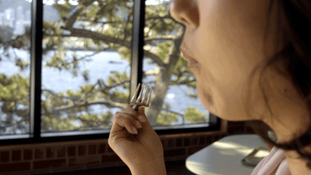 창가에서 케이크를 포크로 떠먹는 여성