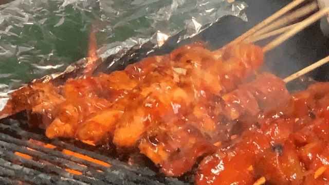 길거리에서 강한 그릴에 구워지는 매운 양념 닭꼬치