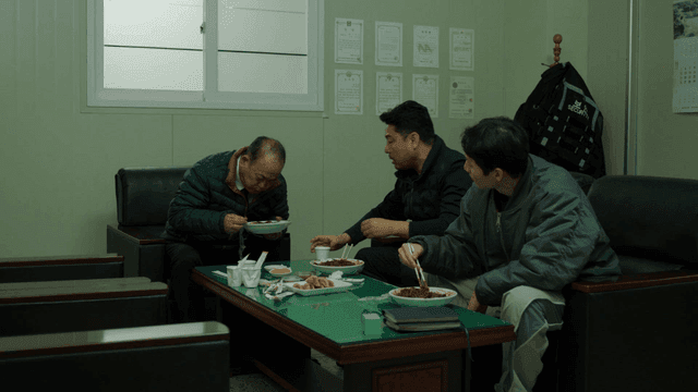 Three men eating jajangmyeon in office