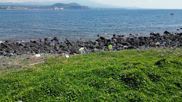 바위 해안의 쓰레기를 청소하는 작업자들