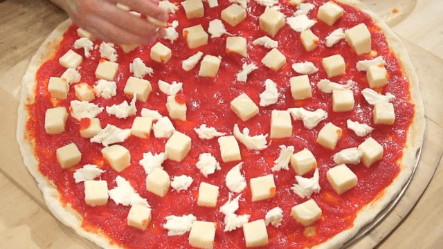 피자 도우 위에 모짜렐라 치즈를 올리는 손