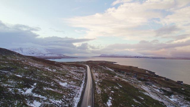 눈 덮인 산과 바다 옆 구불구불한 도로