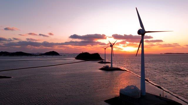 Wind turbines by the sea at sunset