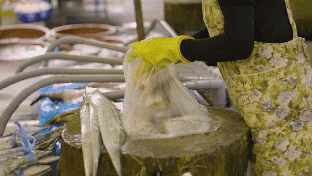 Merchant putting items into plastic bag at market stall