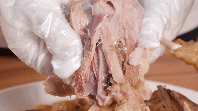 Cooked duck meat being torn by hand