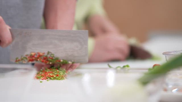 Chopping peppers and green onions on a white cutting board