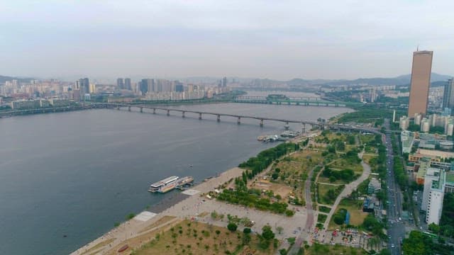 Daytime Cityscape with Riverside Park and Bridge