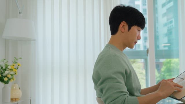 Man Reading a Book by the Window in Bright Living Room