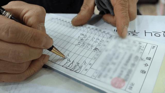 펜으로 영수증을 작성하는 사람