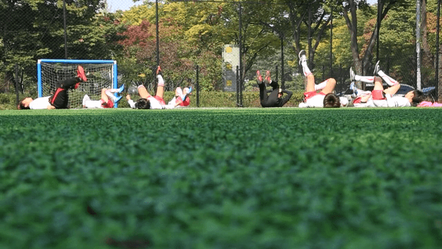 맑은 날 축구장 위에서 스트레칭하는 아이들