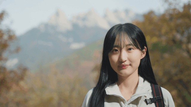 가을 산을 배경으로 서 있는 젊은 여성