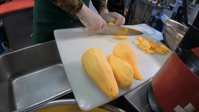 Peeling and slicing sweet potatoes in a kitchen