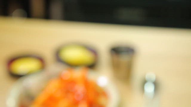 Table with plate of spicy tteokbokki and rice balls and pickled radish