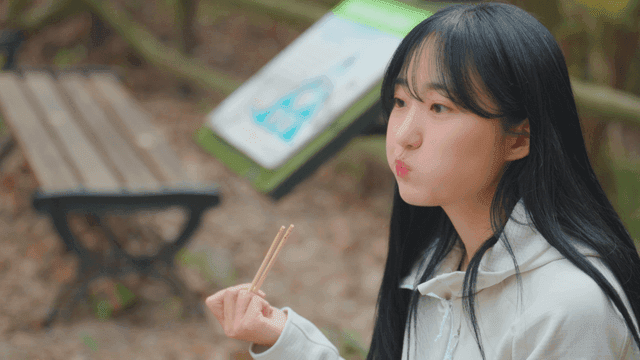 Young woman eating gimbap on bench in autumn forest