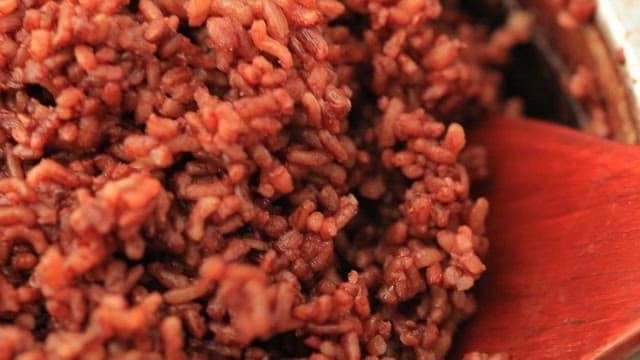 Stirring cooked brown rice with a wooden spatula