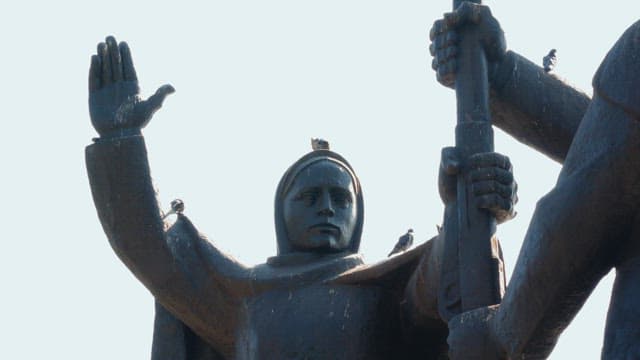 맑은 날 대형 야외 동상 위에 쉬고 있는 비둘기들