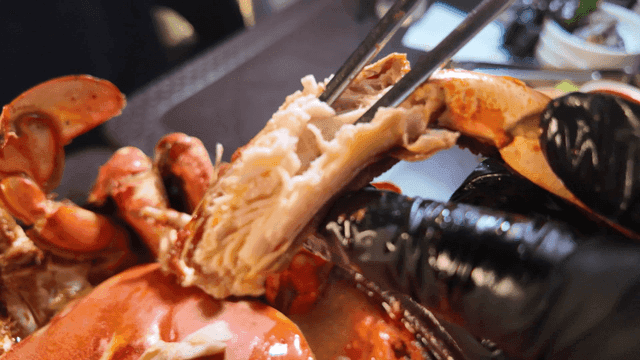 Hands extracting crab meat with chopsticks