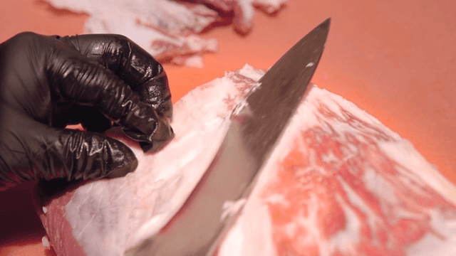 Slicing raw beef with a large knife