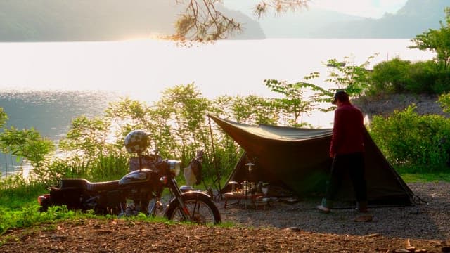 Early morning camping by the serene lakeside with tents and motorbikes