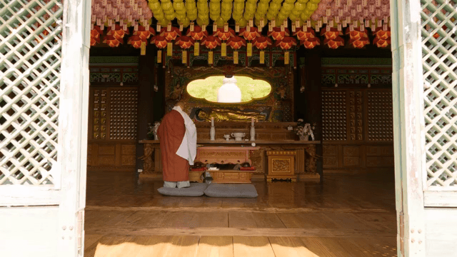 Monk in a temple with a golden Buddha statue