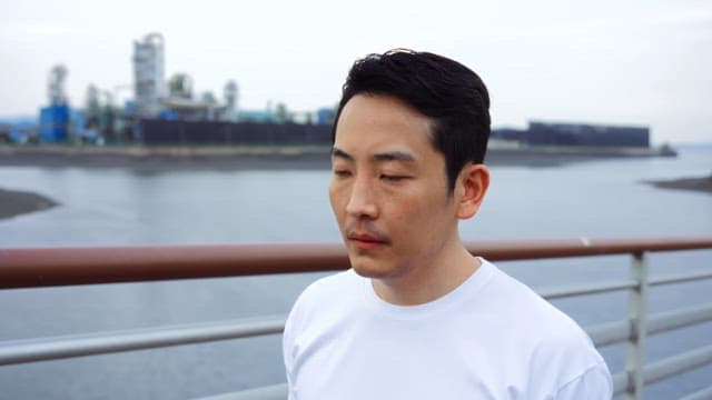 산업 지역 근처 다리 위를 걷는 남자