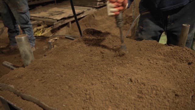 Worker compacting soil with a tool