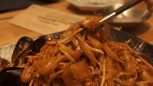 Chopsticks lifting seafood stir-fried noodles