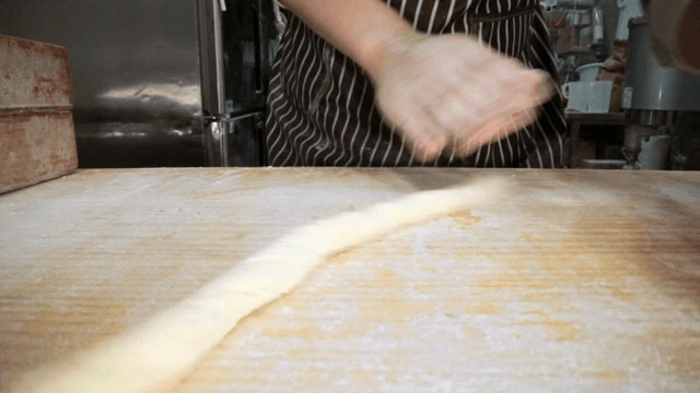 밀가루를 뿌린 표면에서 반죽을 하는 손