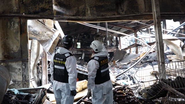 불에 탄 건물 잔해를 조사하고 있는 경찰 조사관들