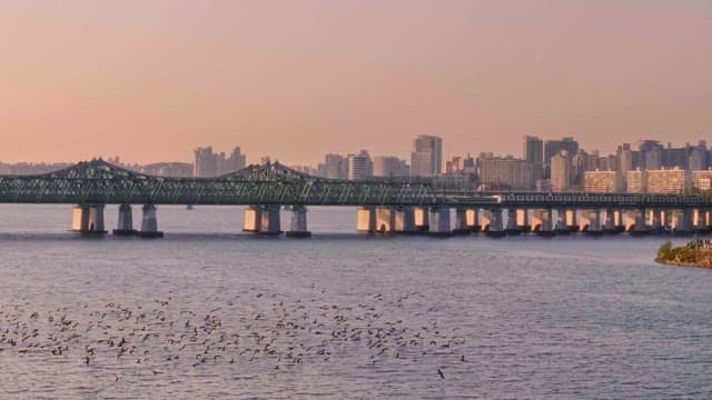 Sunset Over Riverside City Skyline and Steel Bridge