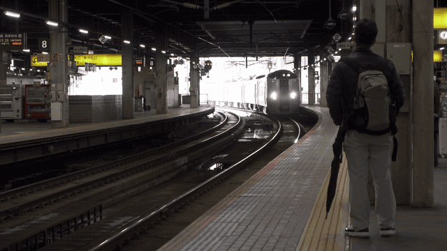 A train approaching a platform with passengers