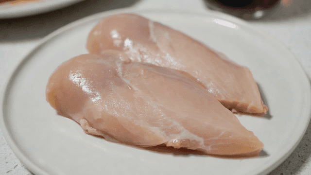 Raw chicken breasts on a white plate