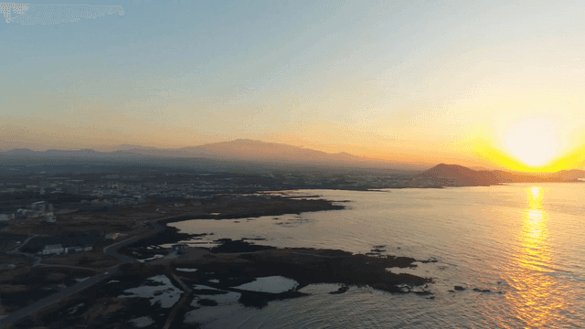 Sunrise over sea next to coastal fields